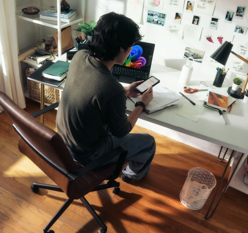 Man working at desk with laptop and phone.