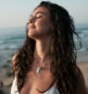 Woman with closed eyes and wet hair at the beach.